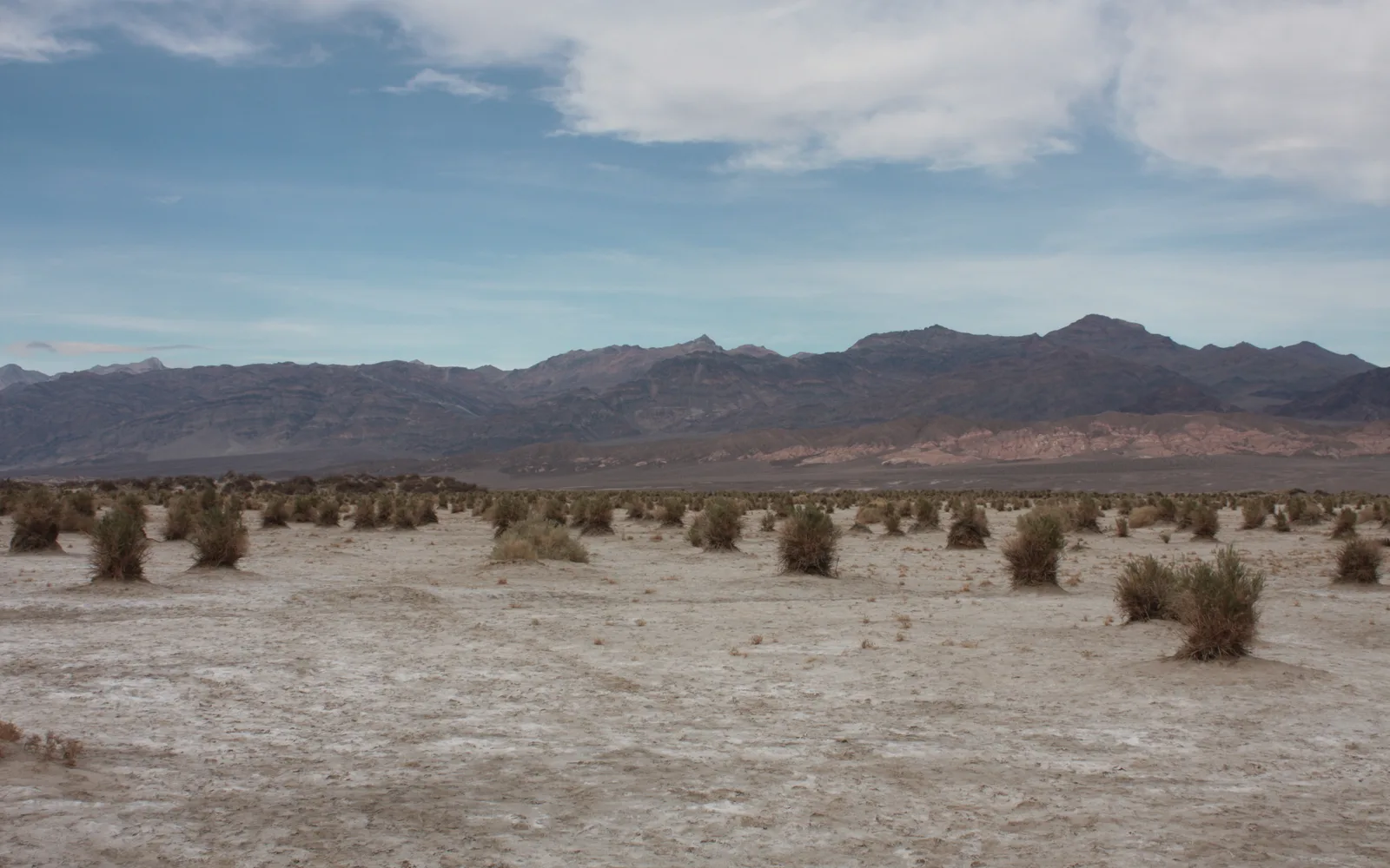 Desert mountain valley with rocky peaks and layered desert landscape under clear sky